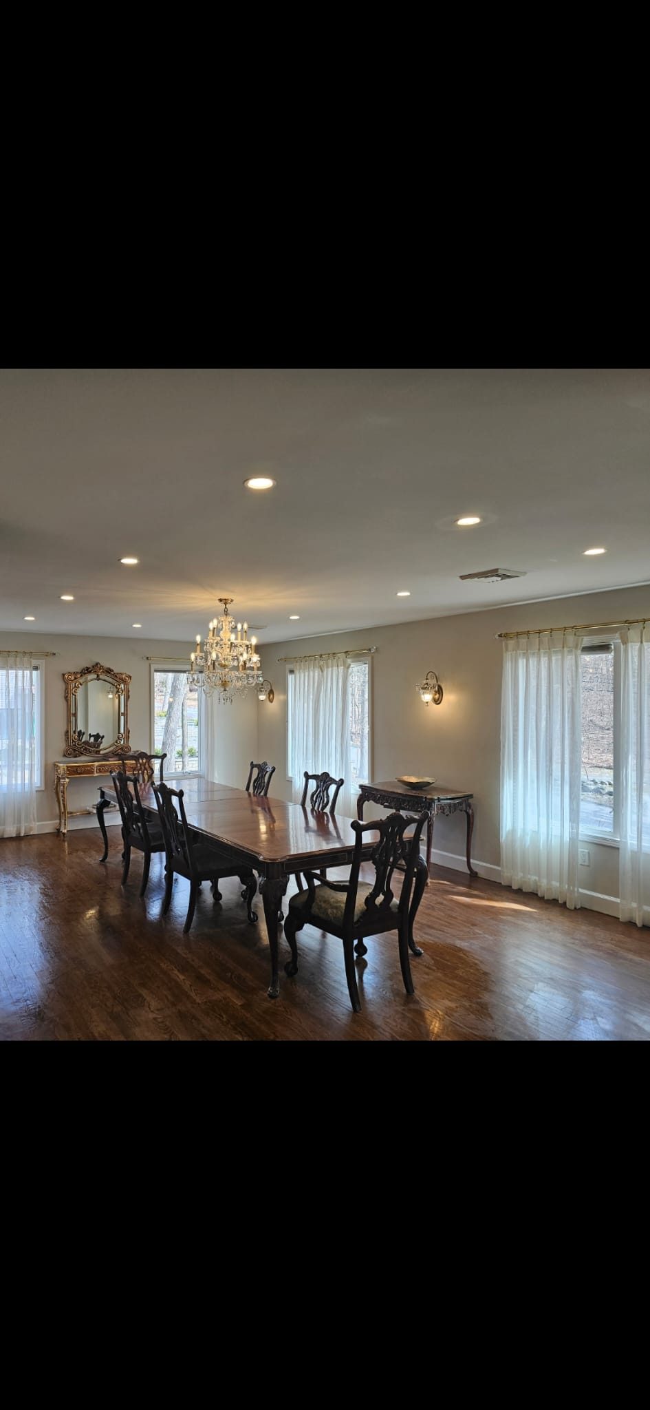 Dining room with a chandelier centred over the table and recessed downlights around it