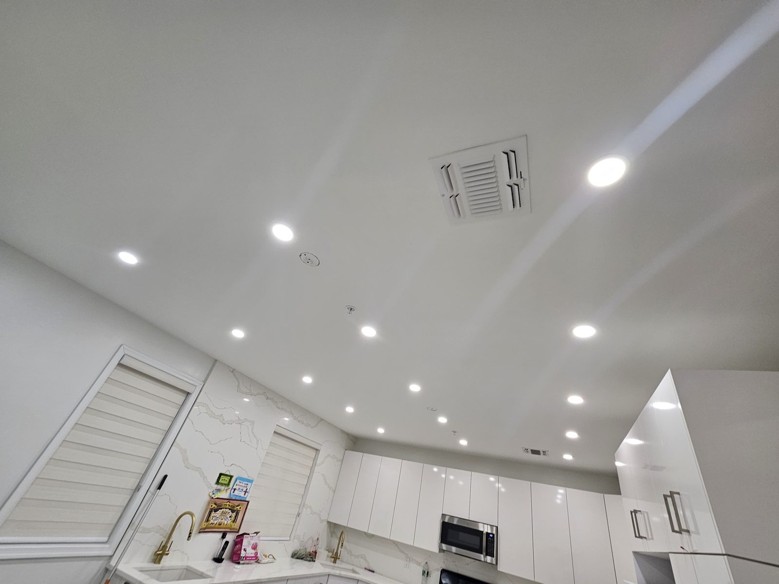 White kitchen with recessed downlights across a sloped ceiling