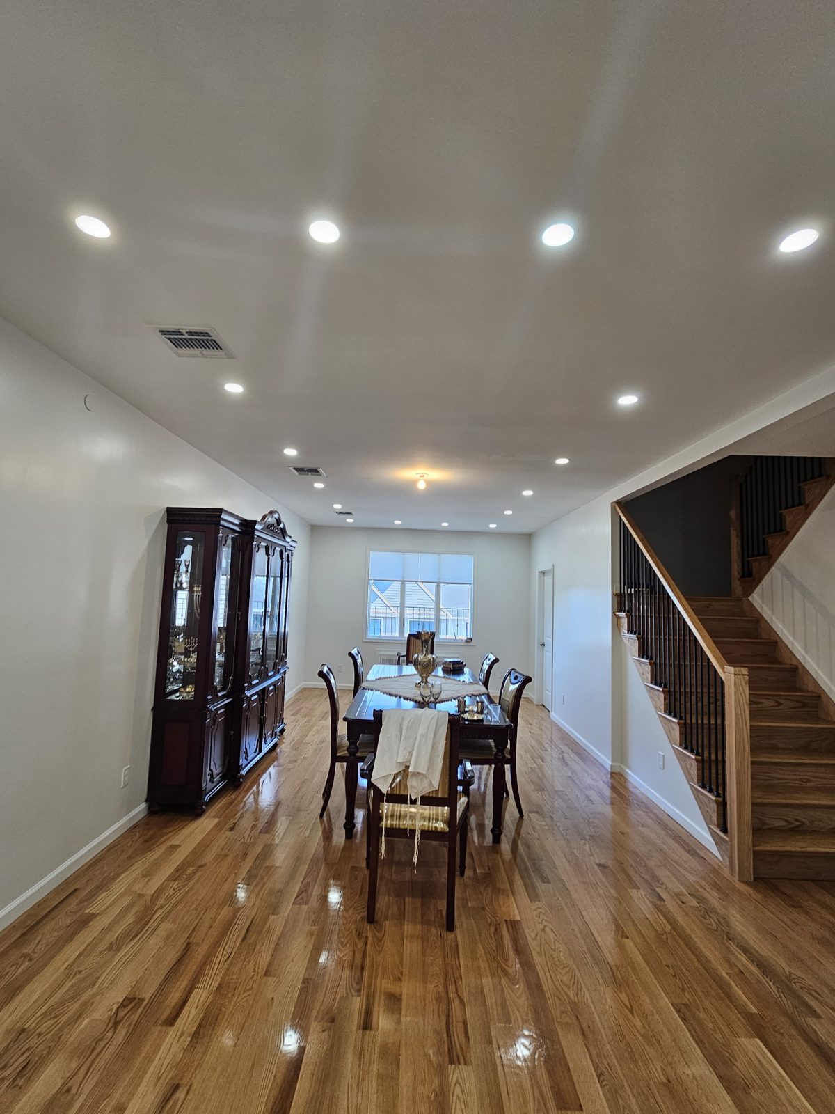 Dining table beside a staircase lit by recessed ceiling downlights