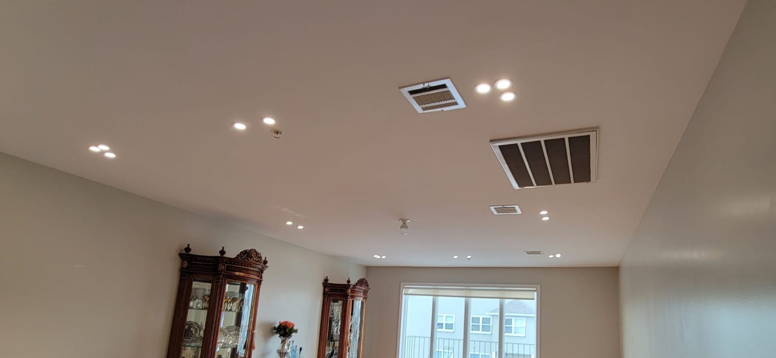 Living space with tall cabinetry and recessed downlights across a wide ceiling