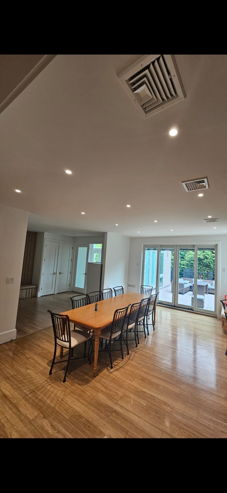 Dining table on hardwood floors lit by recessed downlights beside garden doors