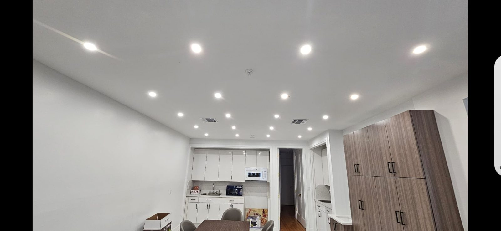 Kitchen and corridor lit by a clean run of recessed ceiling downlights