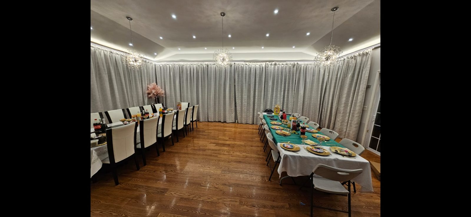 Banquet room with draped walls, LED cove lighting, and pendant fixtures above long tables