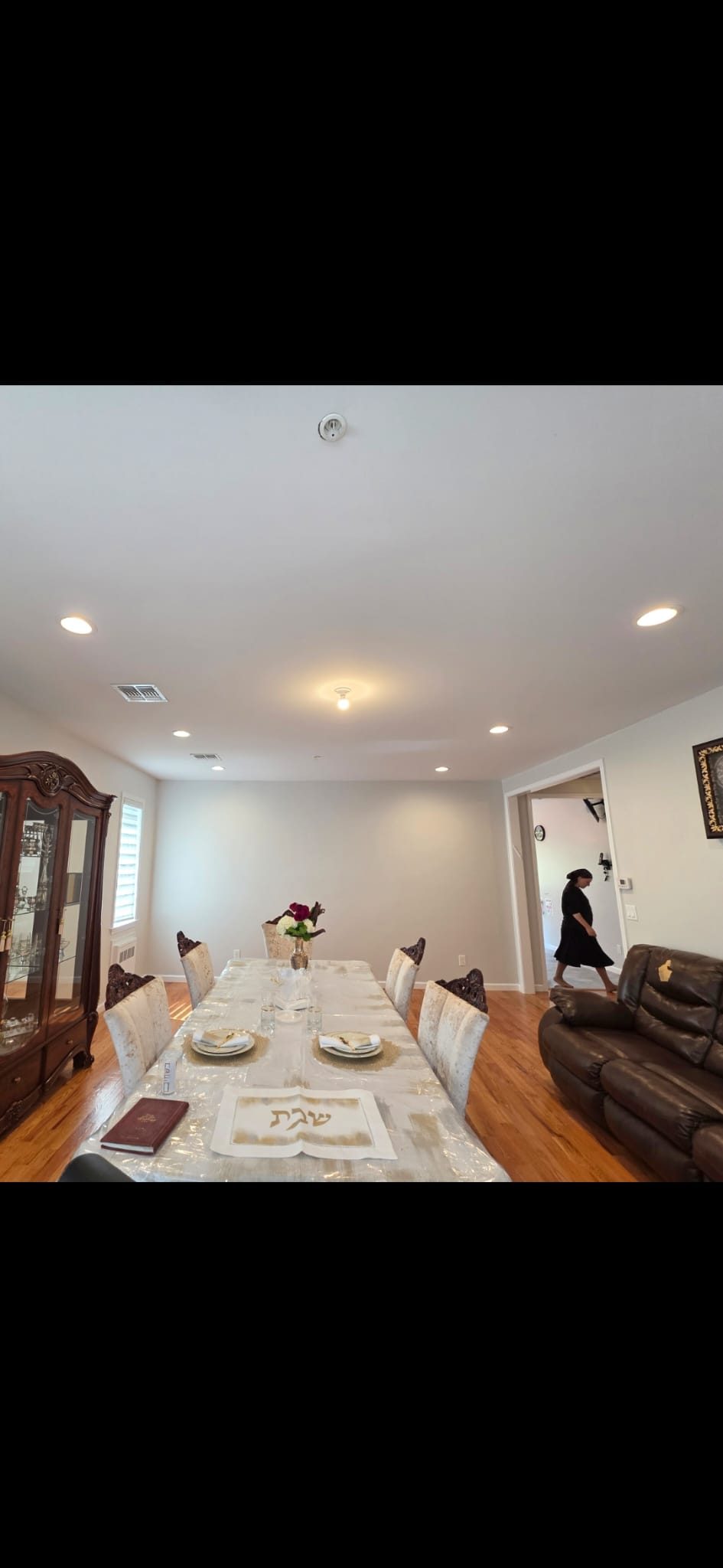 Dining room with dark cabinetry and a set table lit by recessed downlights