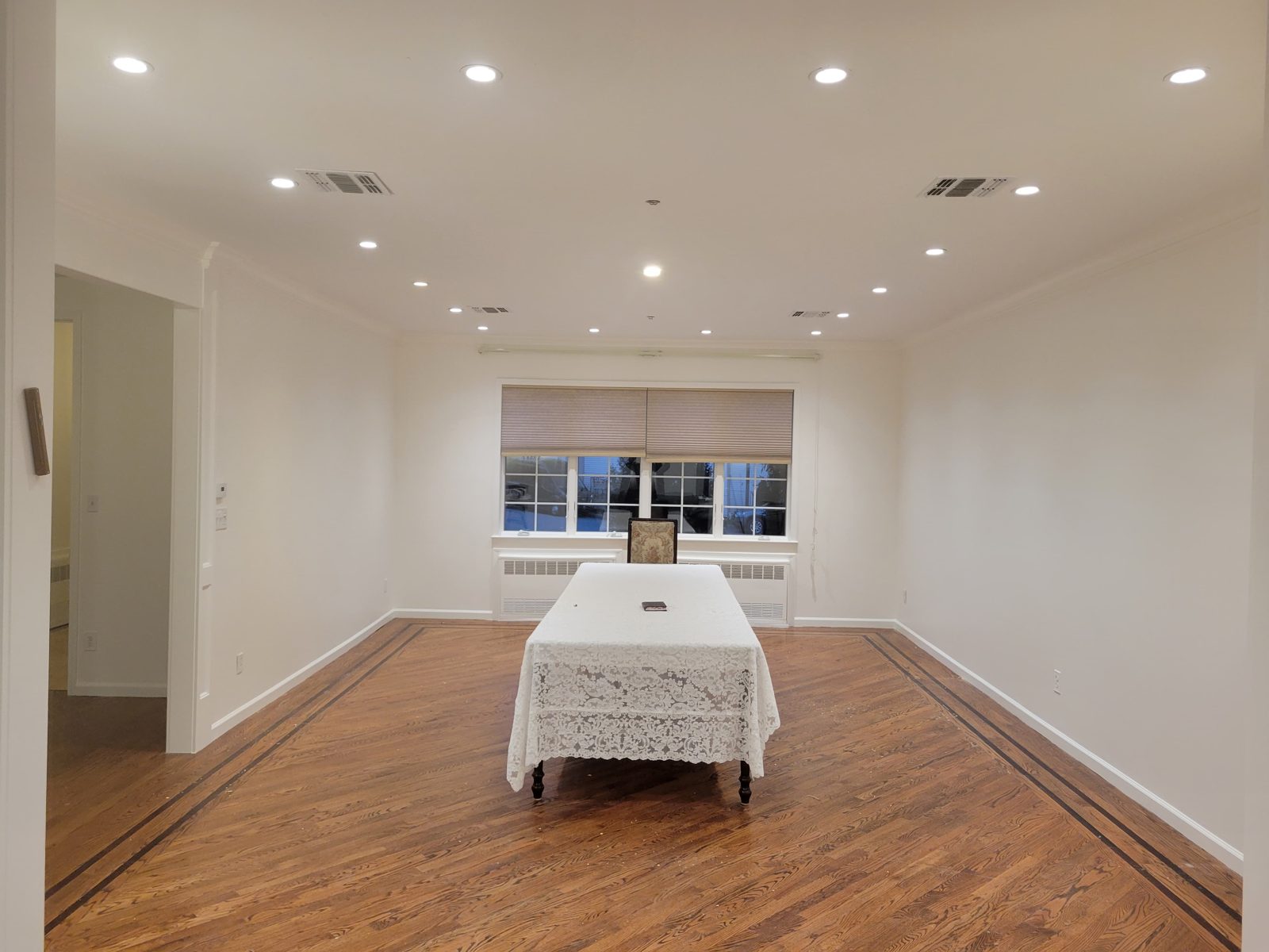 Long room with a white-clothed table and recessed ceiling lighting