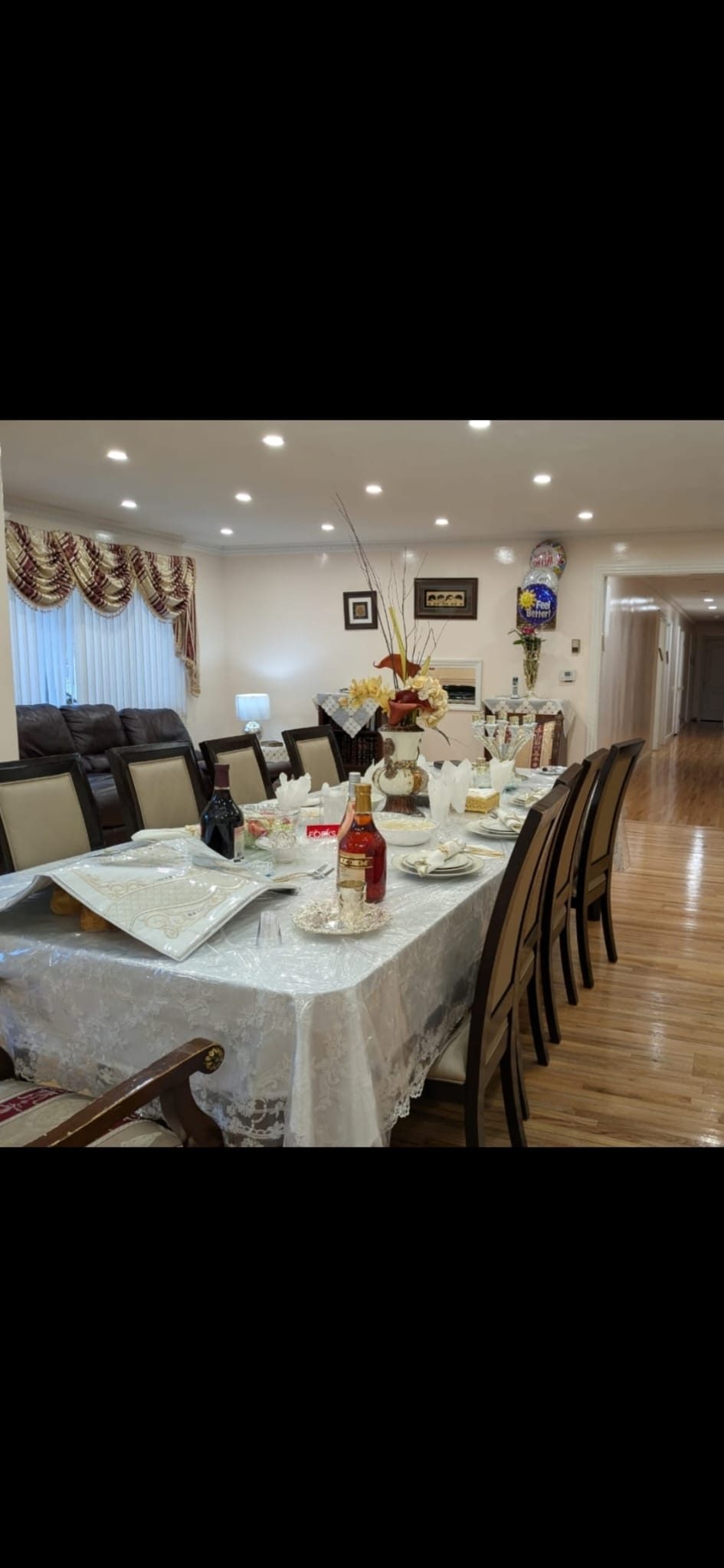 Formally set dining table lit by warm recessed downlights beside draped windows