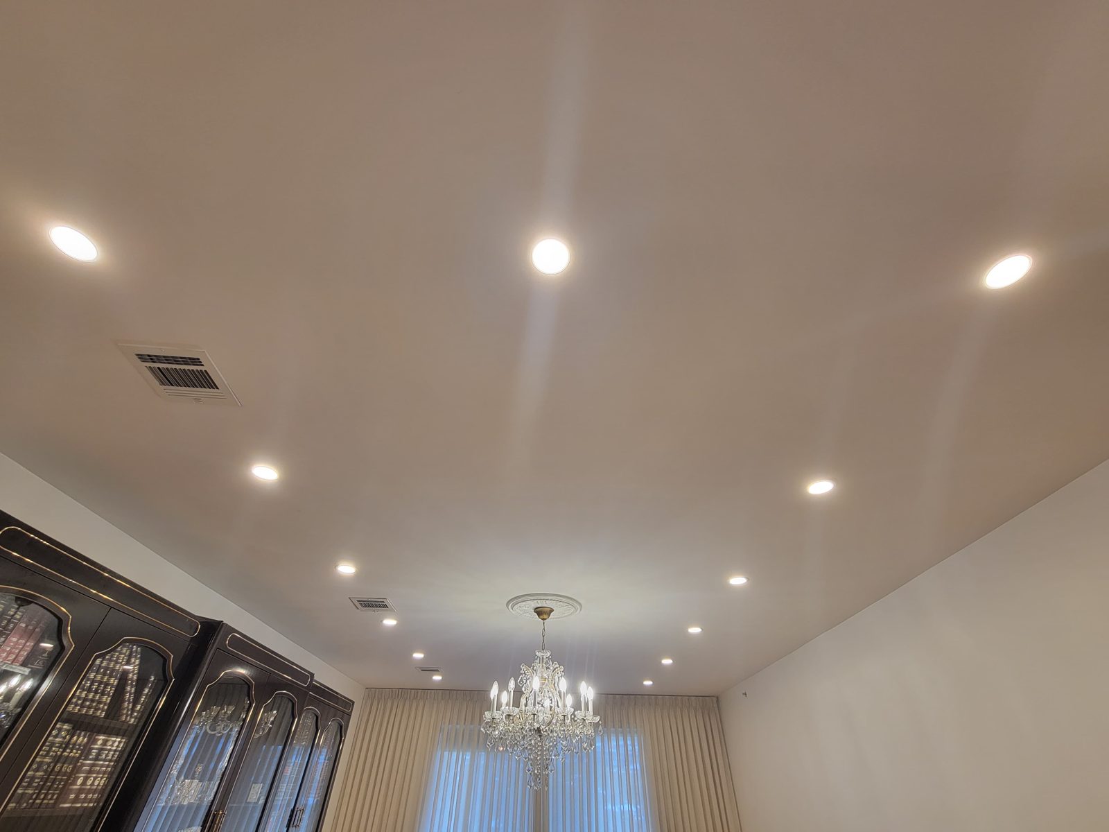Room with a chandelier and recessed downlights above a wooden floor