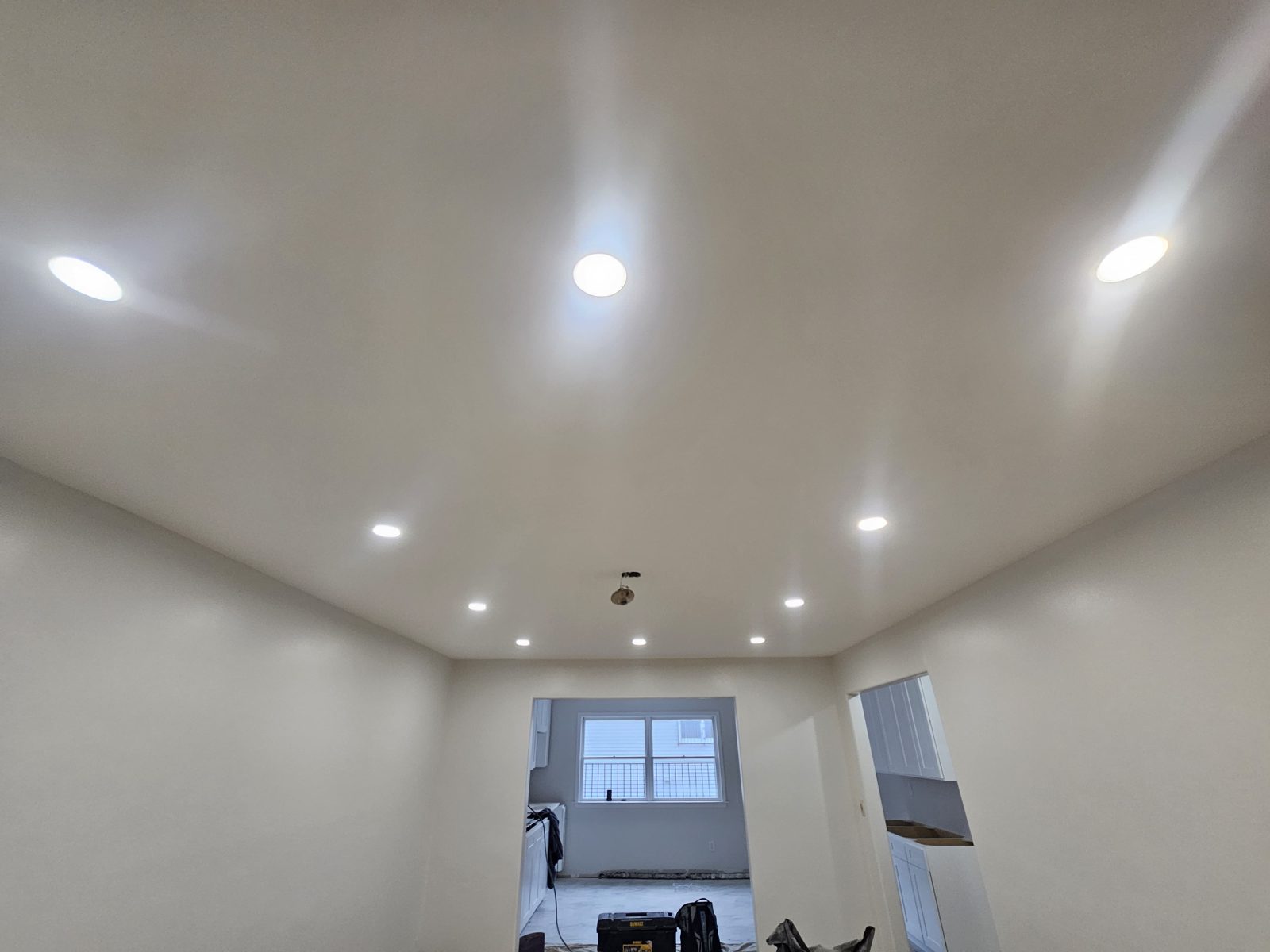 Vaulted white ceiling with recessed downlights above a bright room