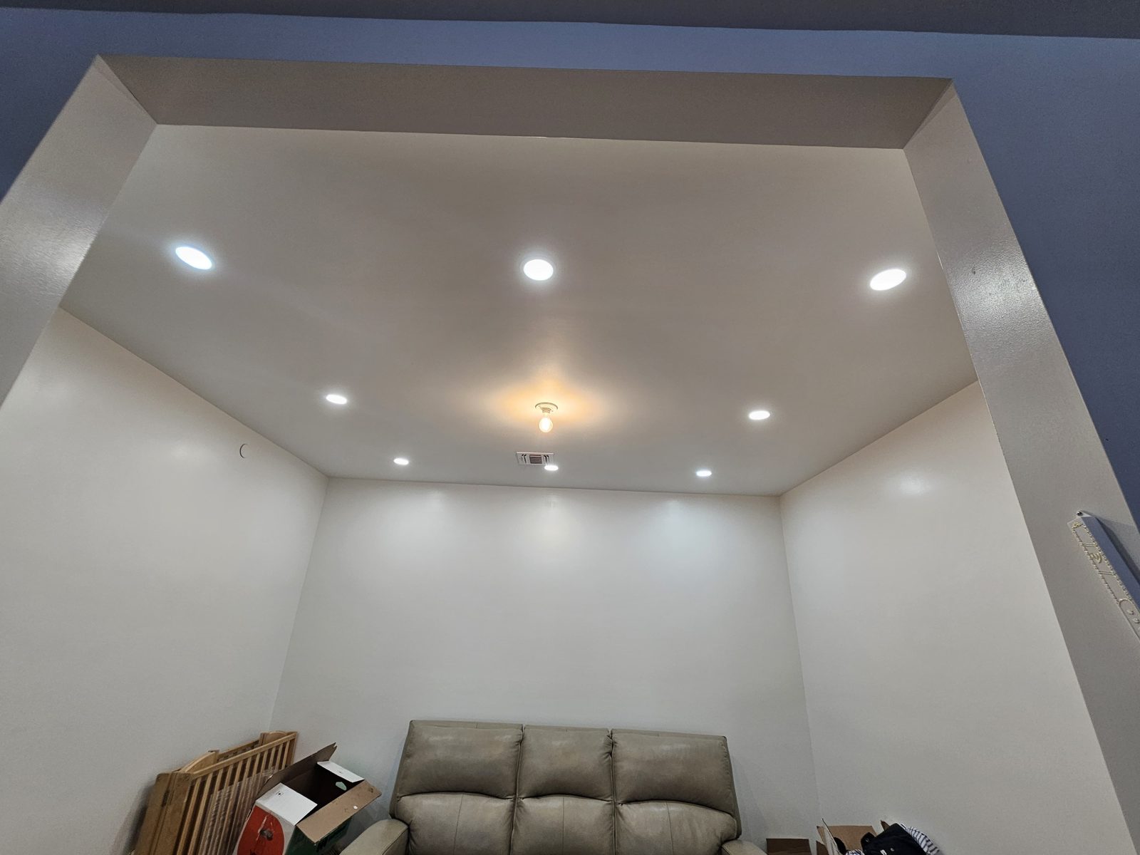 Lounge with sofas lit by recessed downlights across a wide ceiling