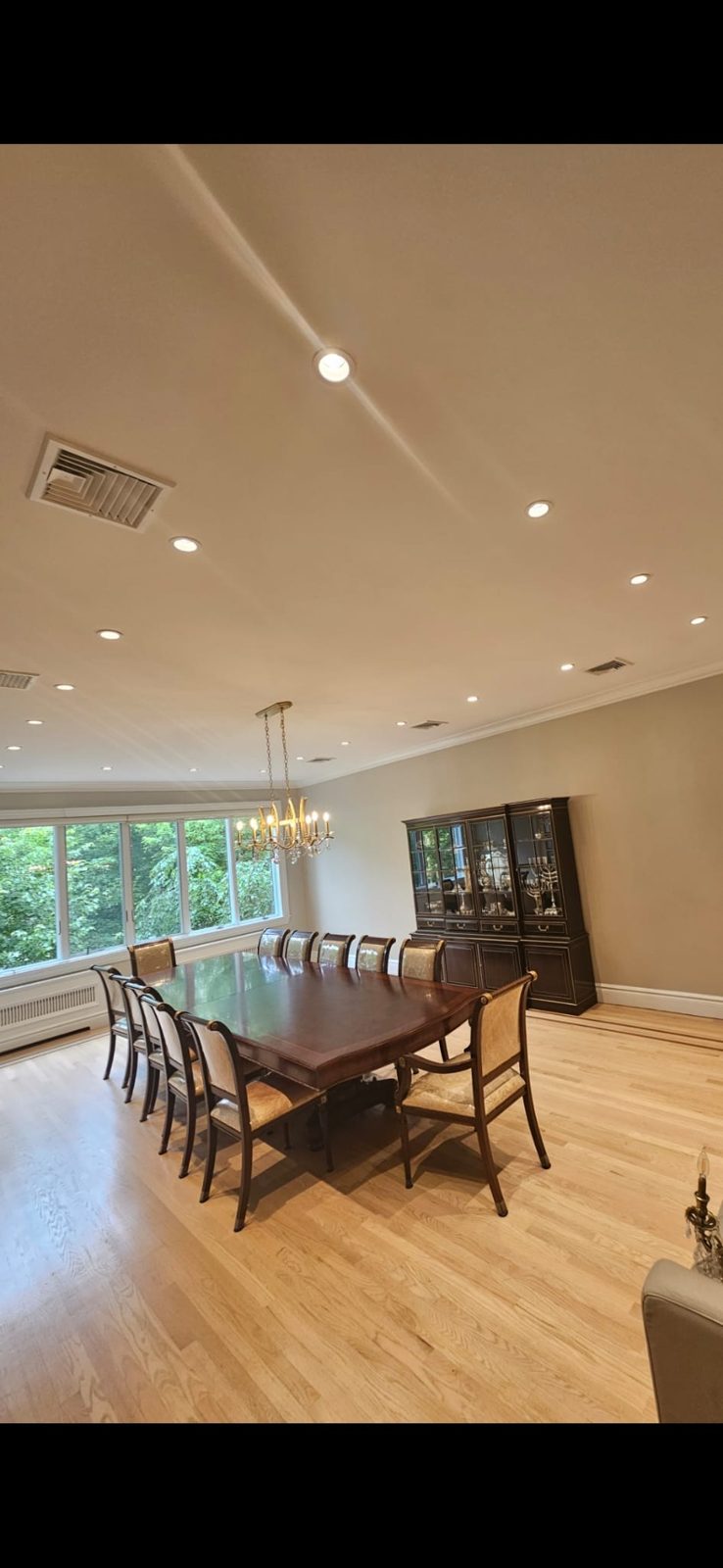 Formal dining room with a long wooden table lit by recessed ceiling lighting