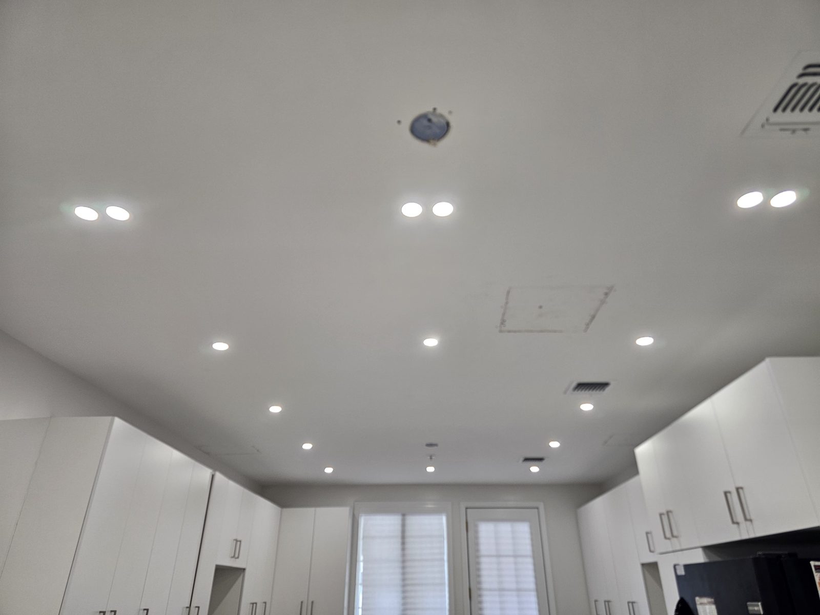 Bright room with shuttered windows lit by recessed ceiling downlights