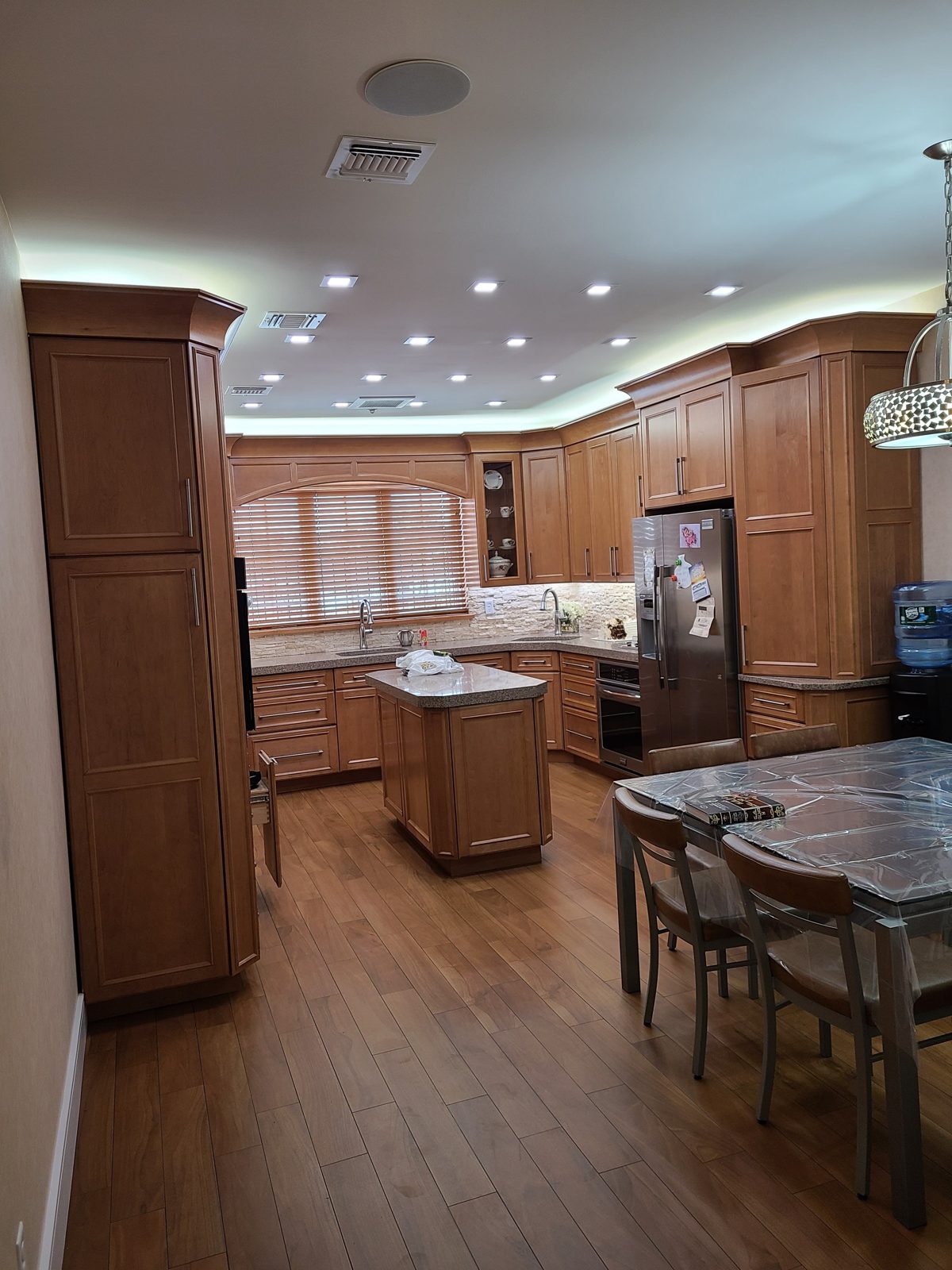 Traditional wood kitchen lit by recessed downlights and island pendants