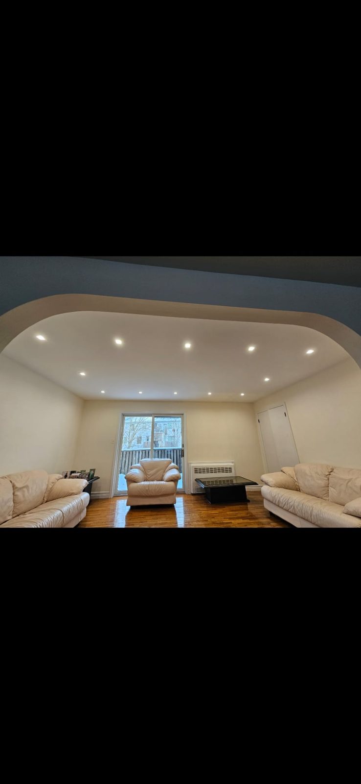 Living room with a curved ceiling, cove lighting, and recessed downlights above a sectional sofa