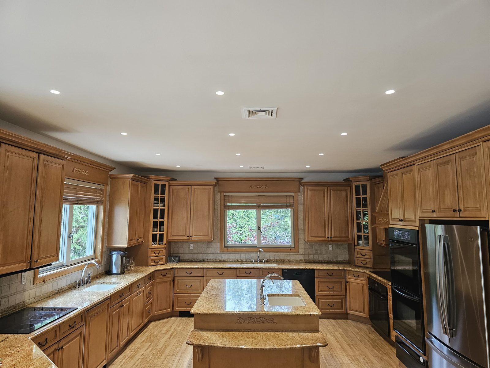 Wood kitchen with a large island lit by recessed ceiling downlights