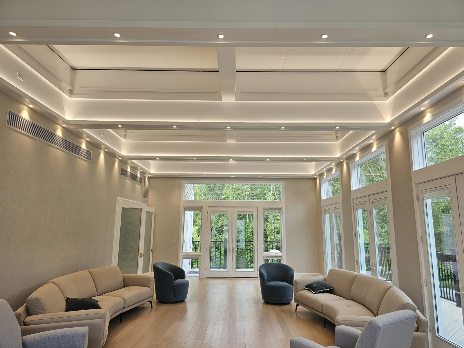 Living room with a coffered ceiling, recessed downlights, and sofas facing garden doors