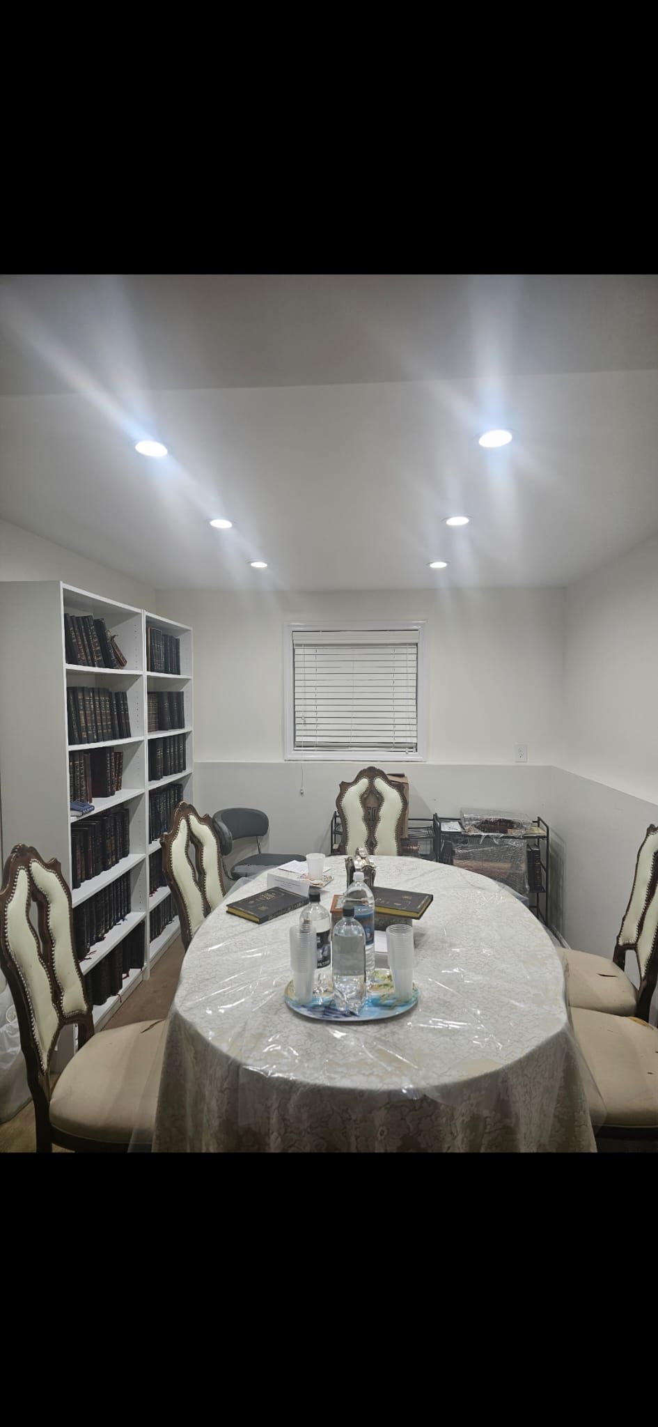 Round dining table and built-in shelving lit by recessed ceiling downlights