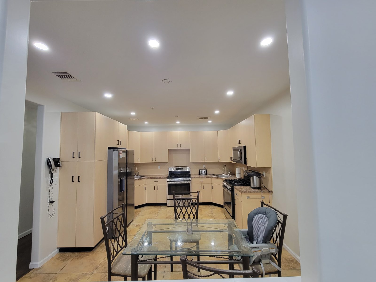Kitchen and glass dining table lit by recessed ceiling downlights