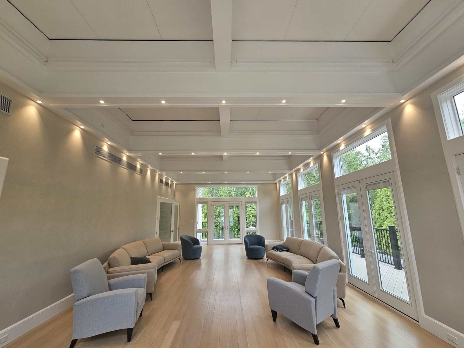 Large lounge with a coffered ceiling, recessed downlights and armchairs