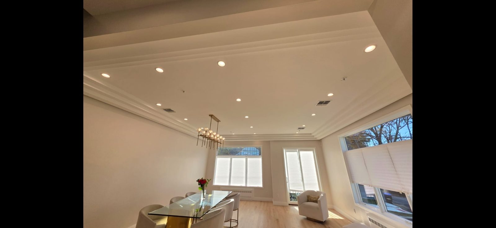 Open lounge with a modern linear chandelier and recessed ceiling downlights