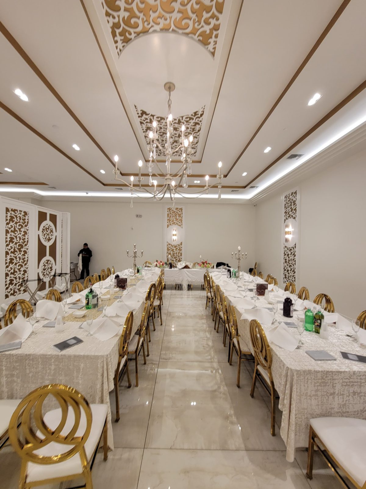 Long banquet table under a decorative ceiling with LED light lines and chandeliers