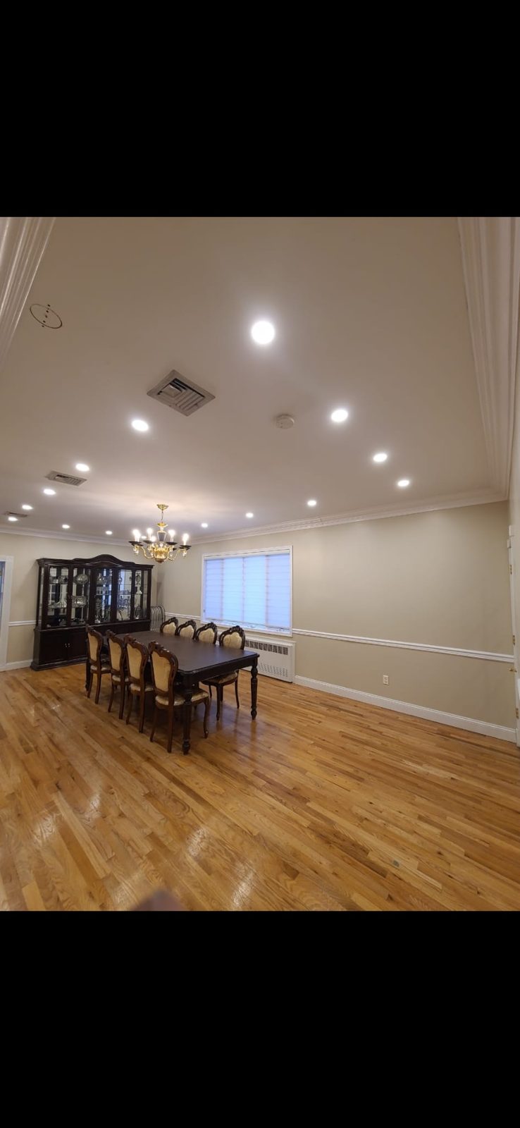 Open dining area with evenly spaced recessed ceiling downlights over a hardwood floor