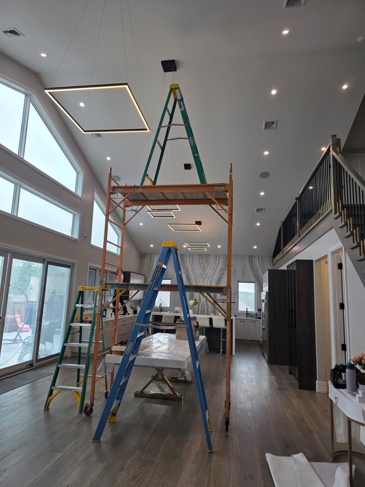 Double-height great room during installation with suspended LED panels