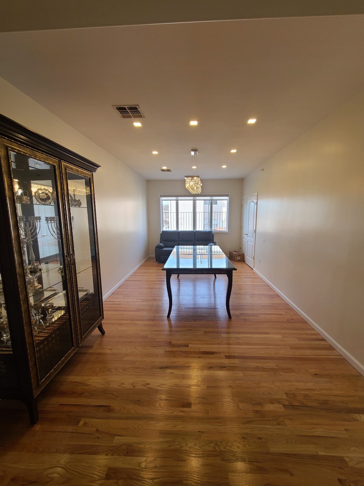 Hardwood hallway and dining space lit by recessed ceiling downlights