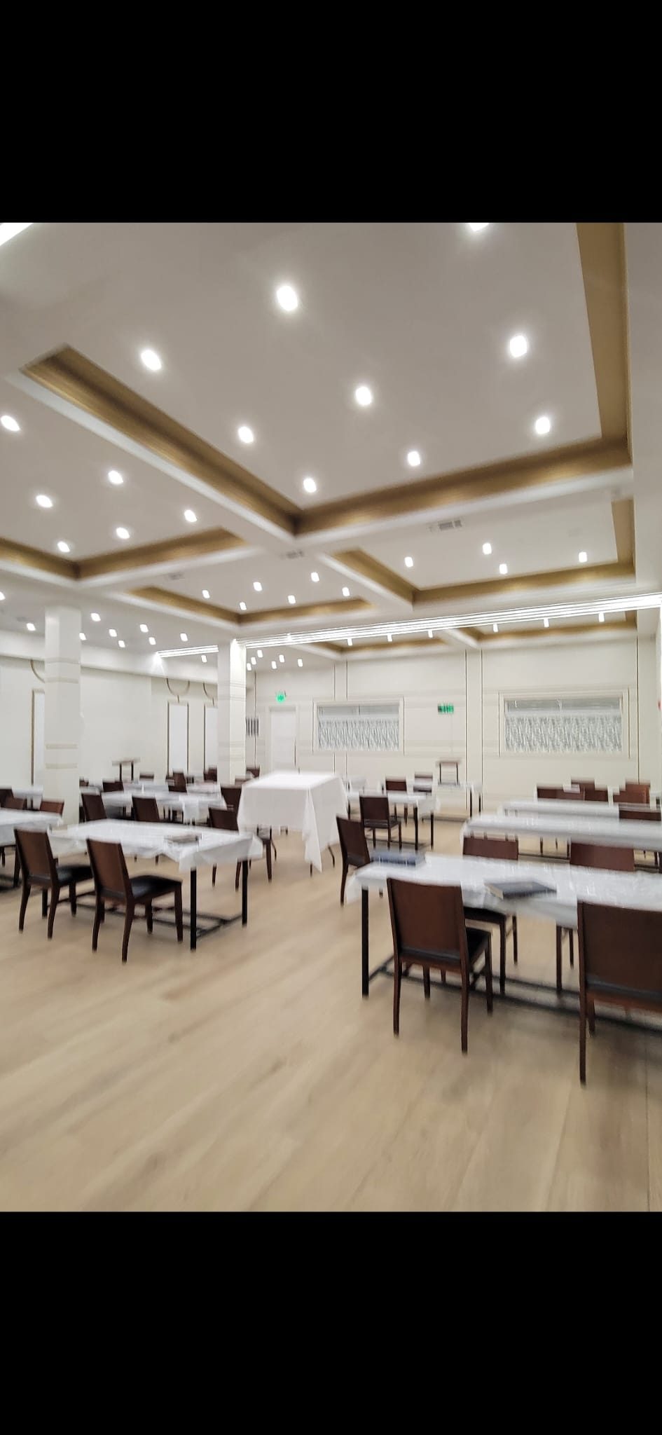 Coffered ceiling hall fitted with an even grid of recessed downlights above tables