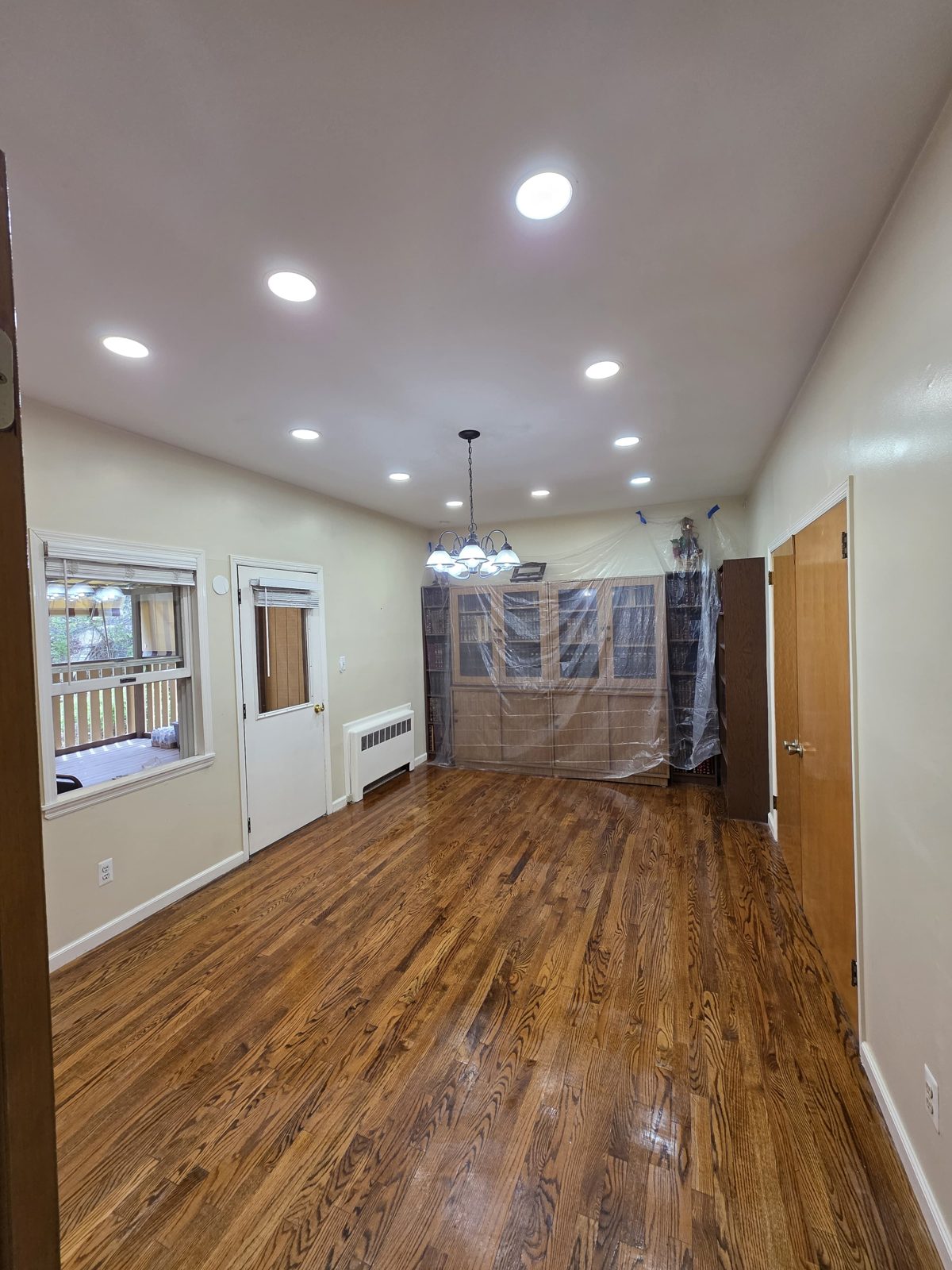 Hallway with a chandelier and recessed downlights on hardwood floors