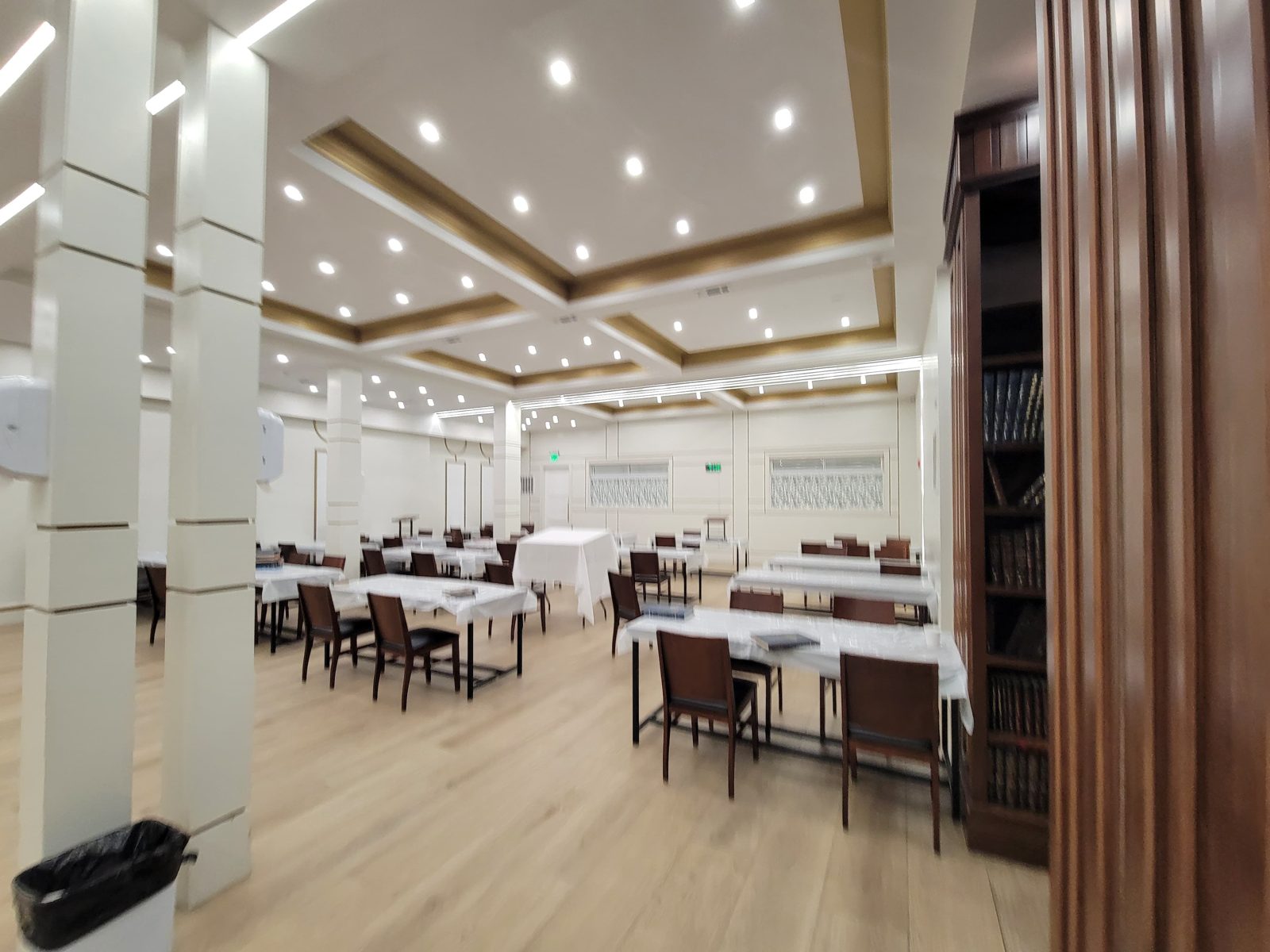 Large hall with columns and rows of recessed ceiling lights above seating