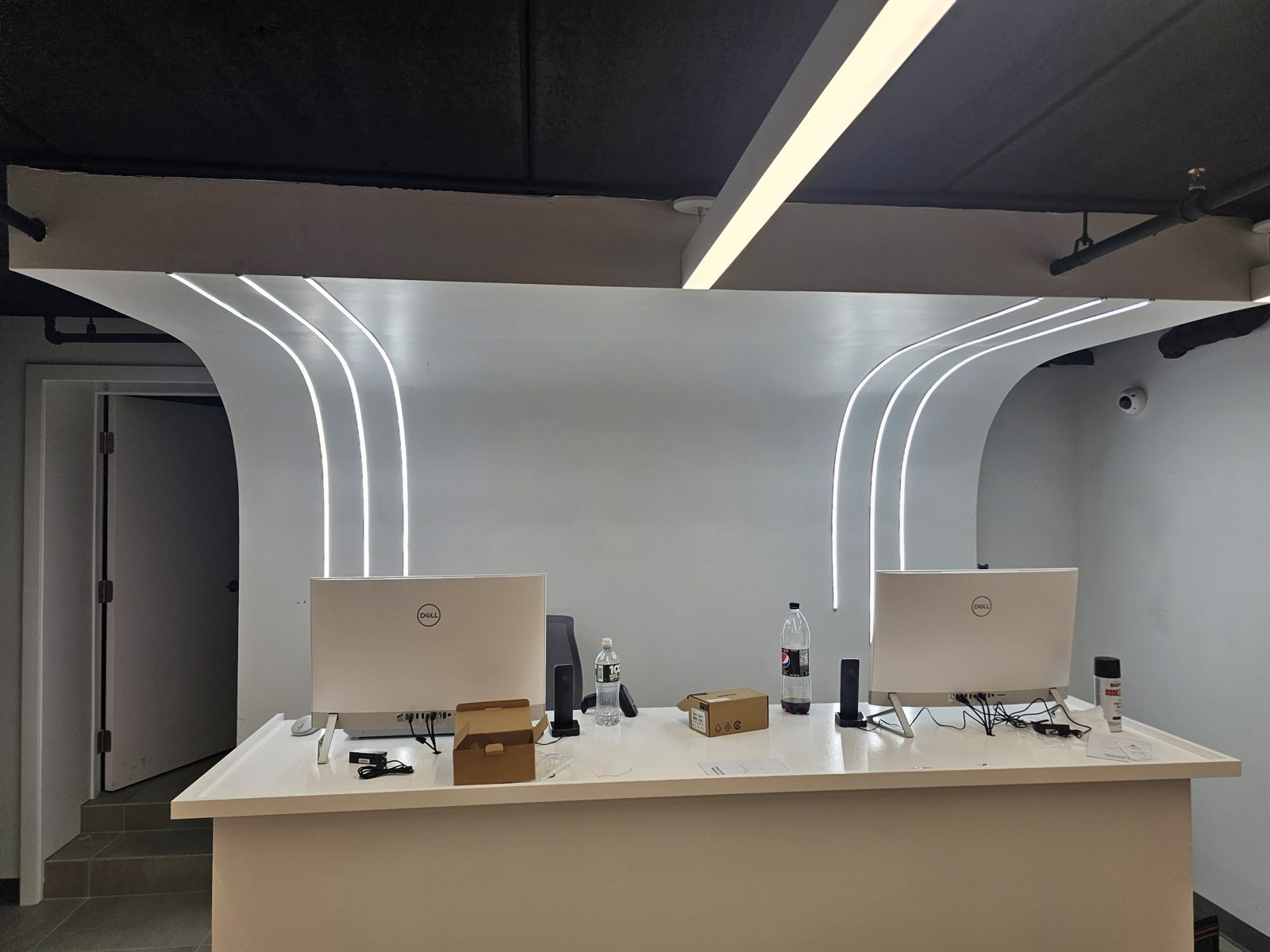 Curved linear LED light lines running across a dark ceiling above a counter
