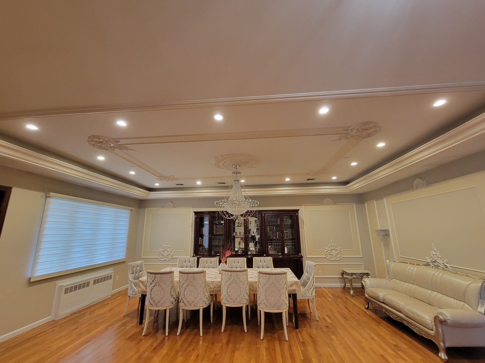Dining table set for a meal under warm recessed lighting and a chandelier