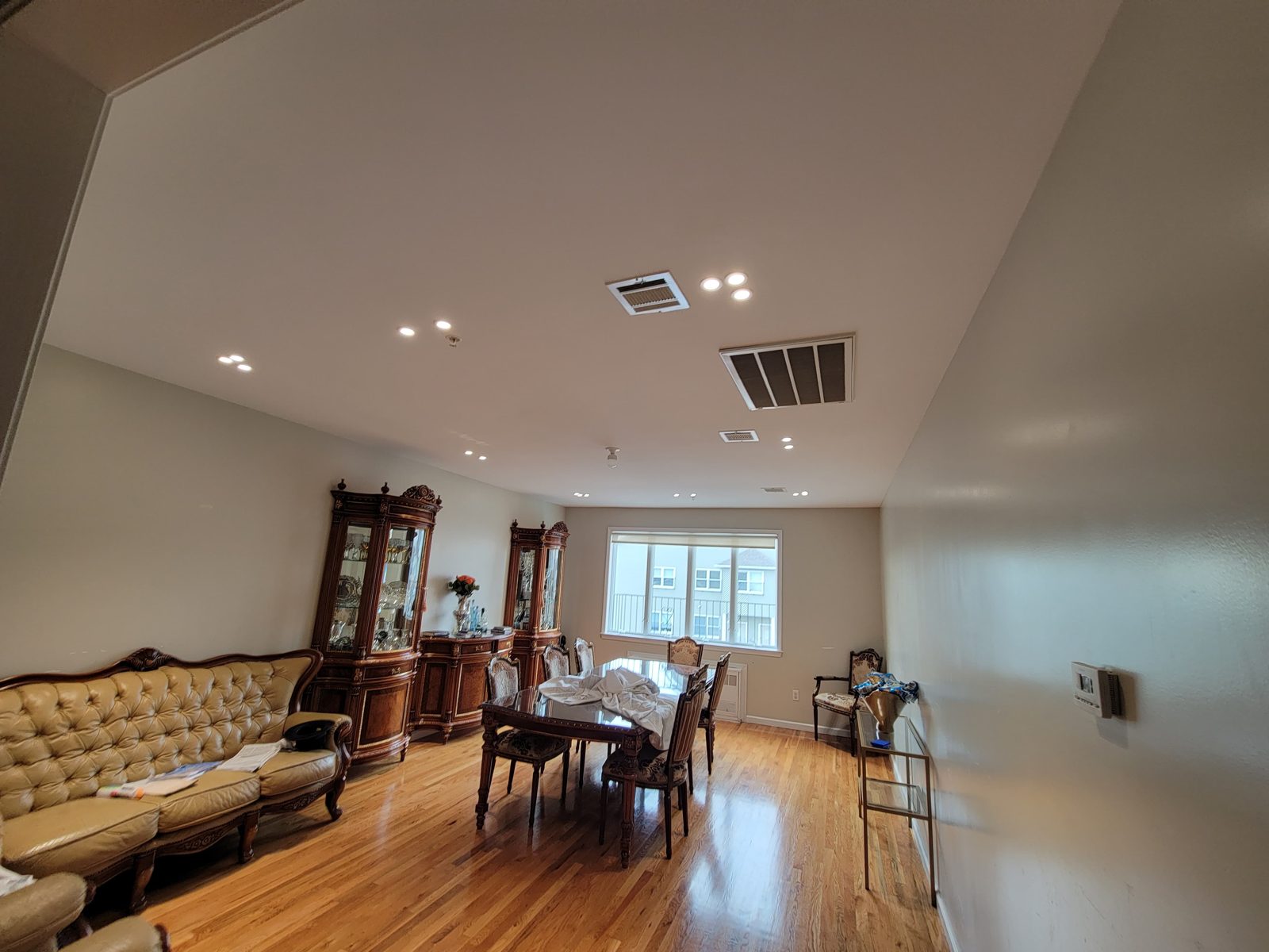 Open living and dining area lit by recessed ceiling downlights