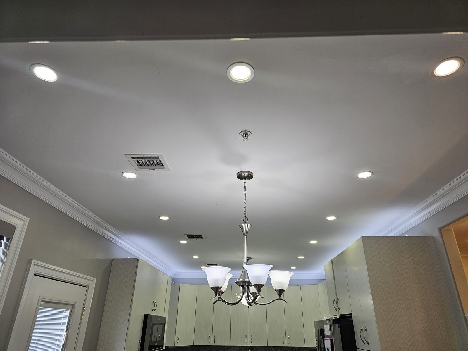 Dining room with a chandelier centred above the table and recessed downlights