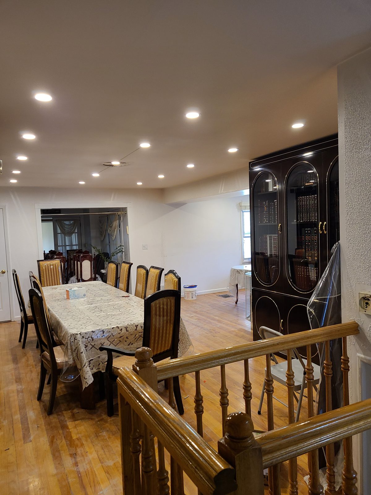 Dining table set under recessed lighting beside a wooden staircase