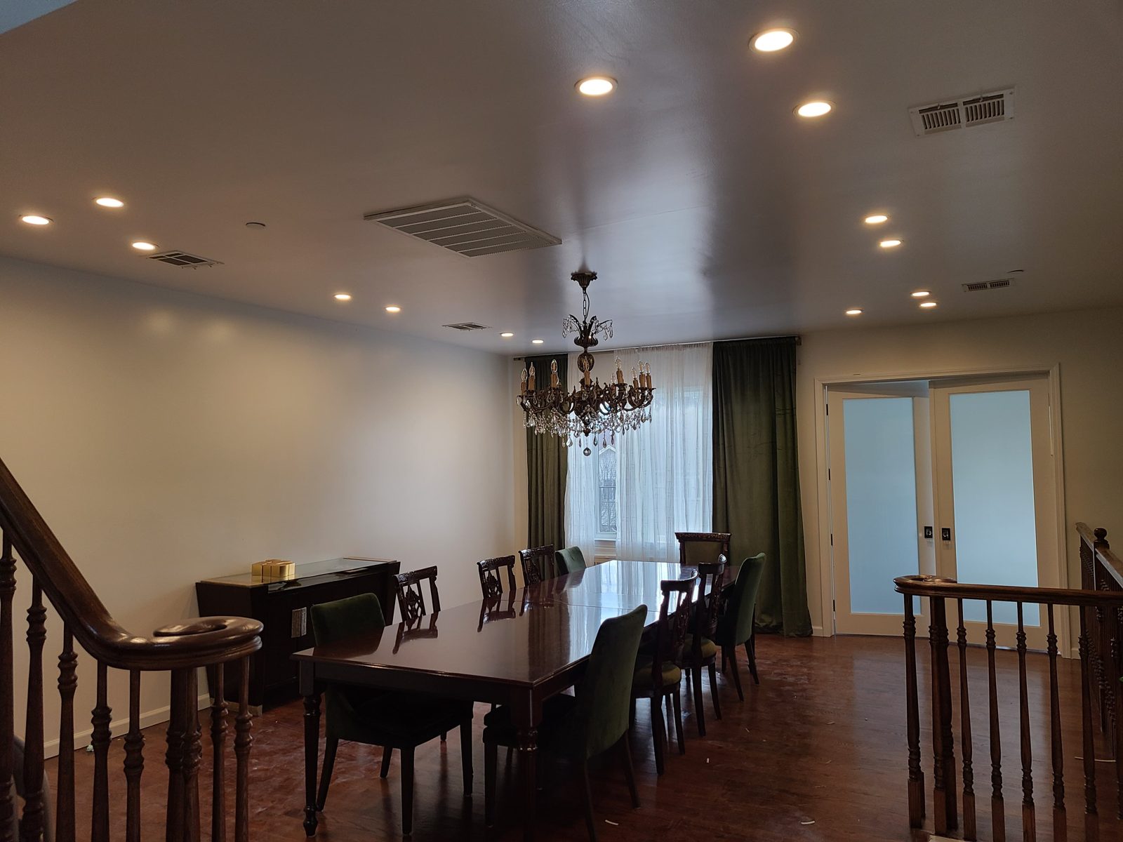Dining room beside a staircase lit with recessed ceiling downlights