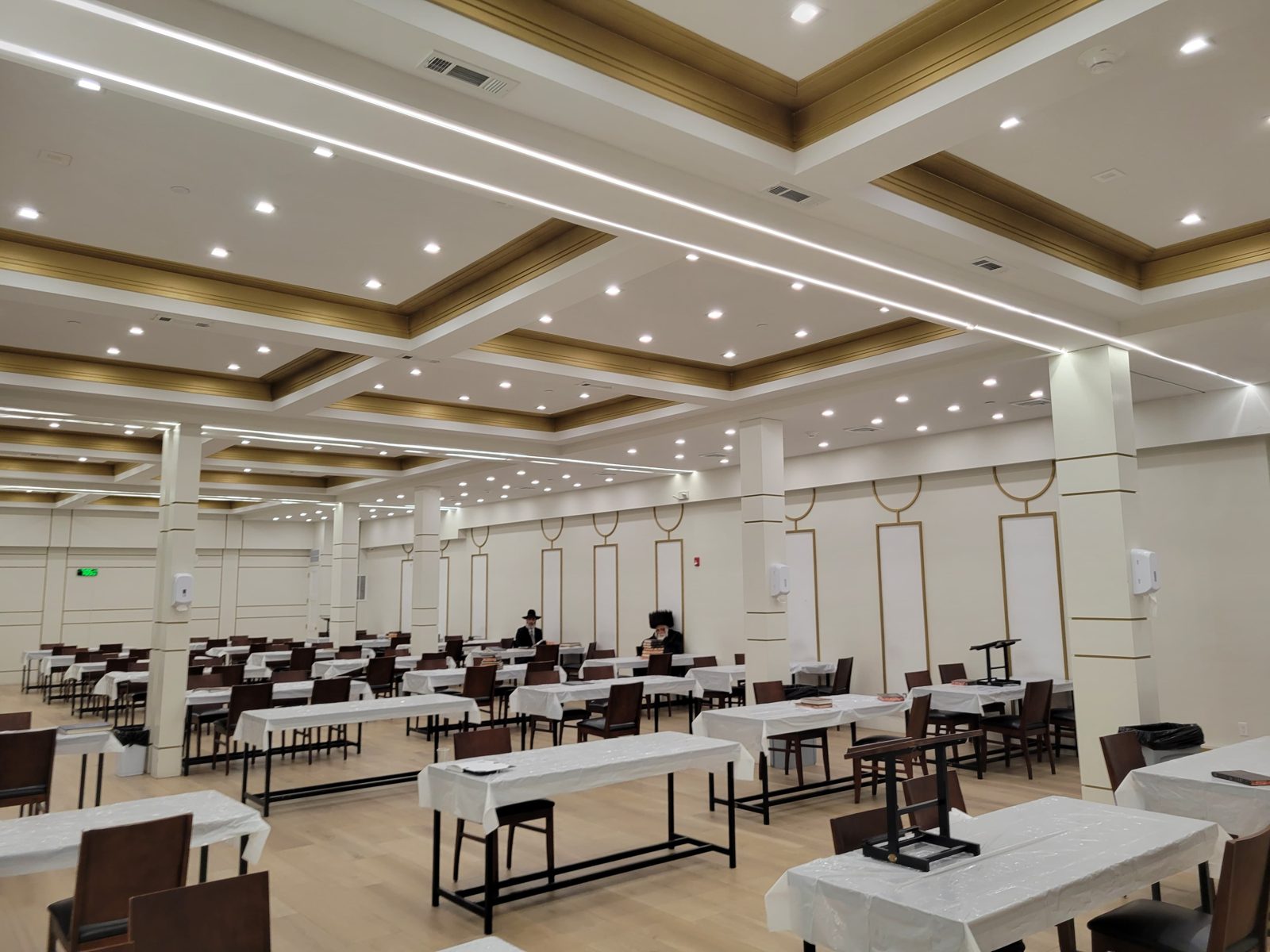 Large event room with a coffered ceiling and recessed downlights above dining tables